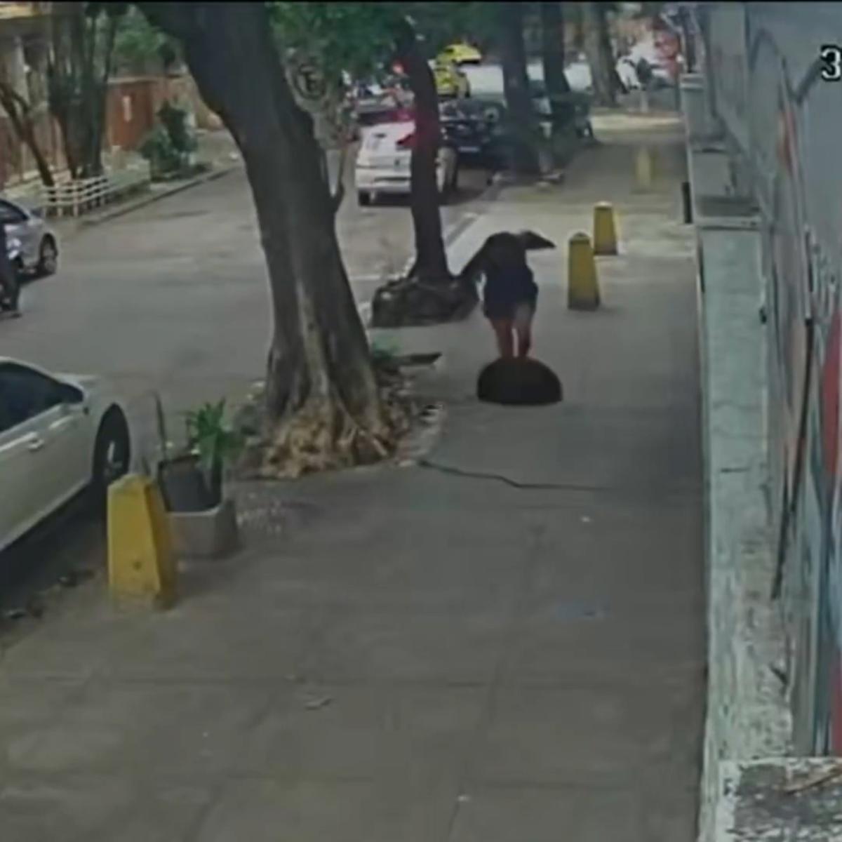 Terrifying moment woman falls down a manhole after cover gave way when she stepped on it (video)